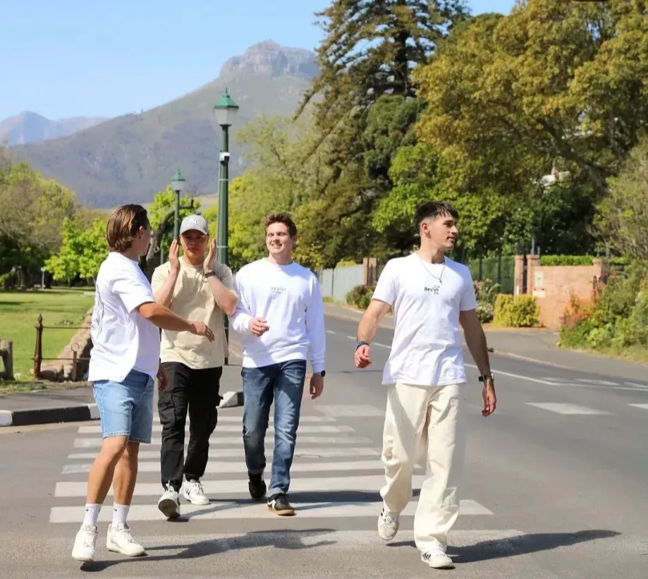 Four friends walking across a street with mountains behind them